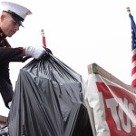 Aidan Jordan, a U.S. Marine Corps boot camp graduate, loads a bag of toys in the truck bed of a red pickup labeled “Toys for Tots” parked at the facade of the Walton Avenue Walmart on Saturday.