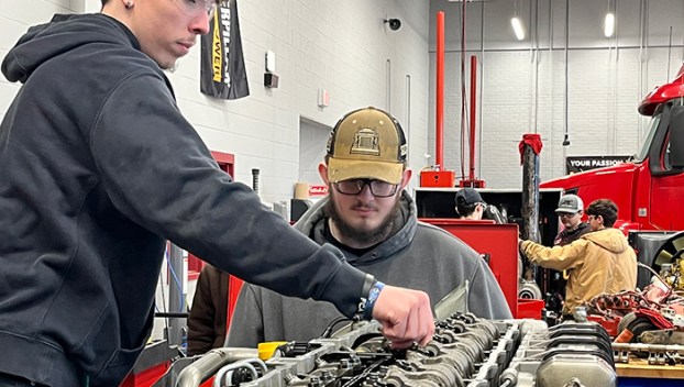 Picture of two diesel program students checking Jake brakes after setting a lash on a diesel engine.
