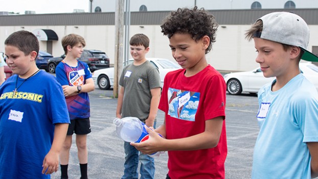 Picture of Rivez Myers, 10, holding onto a Pepsi bottle that’ll be turned into a rocket with vinegar and baking soda Monday.