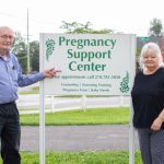 Picture of Don Fricks, executive director of the Pregnancy Support Center of Bowling Green, standing beside shelves of supplies for pregnant mothers and their babies.