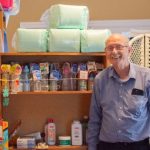 Picture of Don Fricks, executive director of the Pregnancy Support Center of Bowling Green, standing beside shelves of supplies for pregnant mothers and their babies.